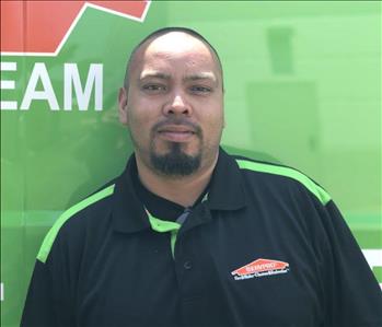 Male employee looking at camera in front of green background